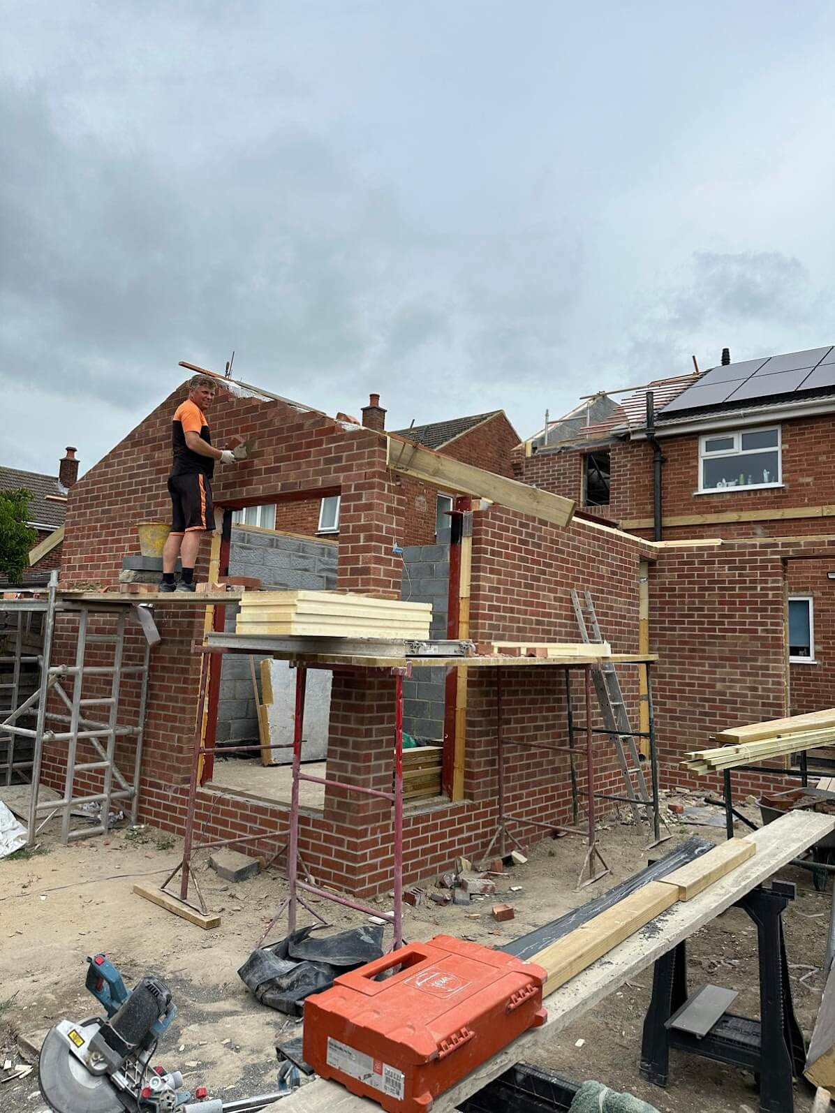A builder from 1st Builders Cambridge on scaffolding constructing a brick extension.